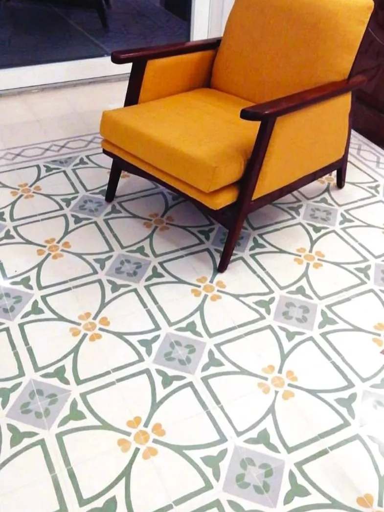A mustard armchair standing on a patterned Maltese cement tile floor