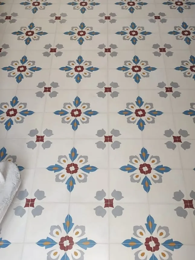 Blue and red floral motifs on a pale cement tile floor