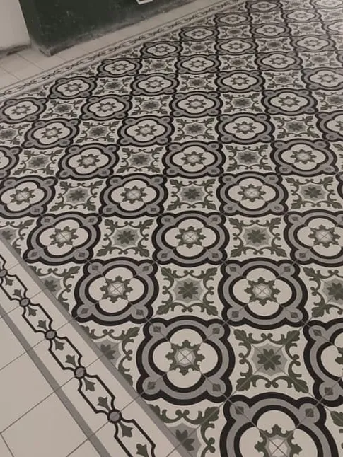 A monochrome patterned tile panel laid as a rug with a dark border