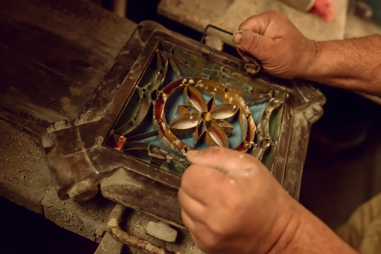 Hands setting the coloured sections of a restored handmade tile mould